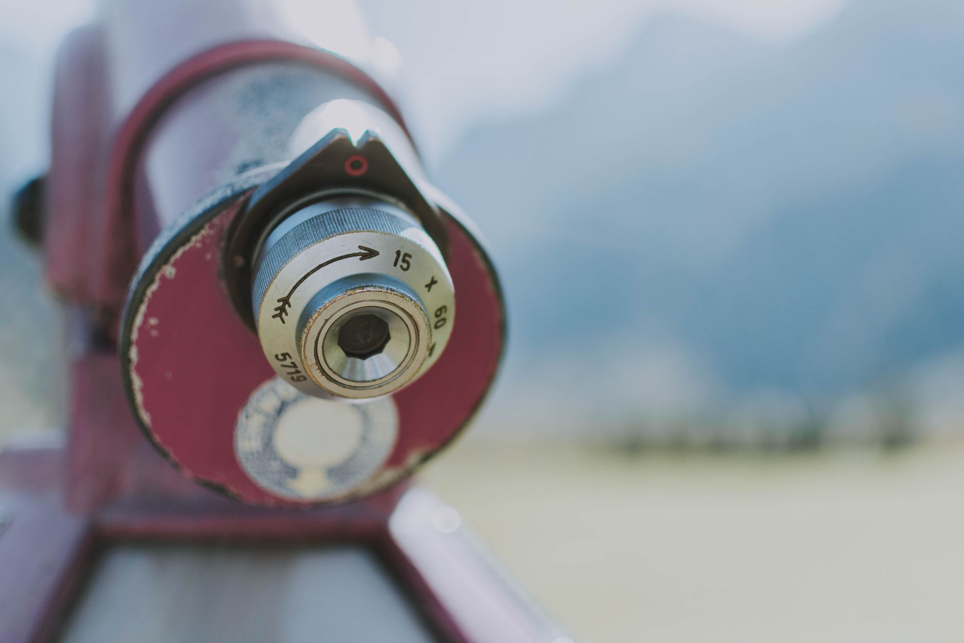 Detailed close-up of an outdoor telescope lens with a blurred natural background.